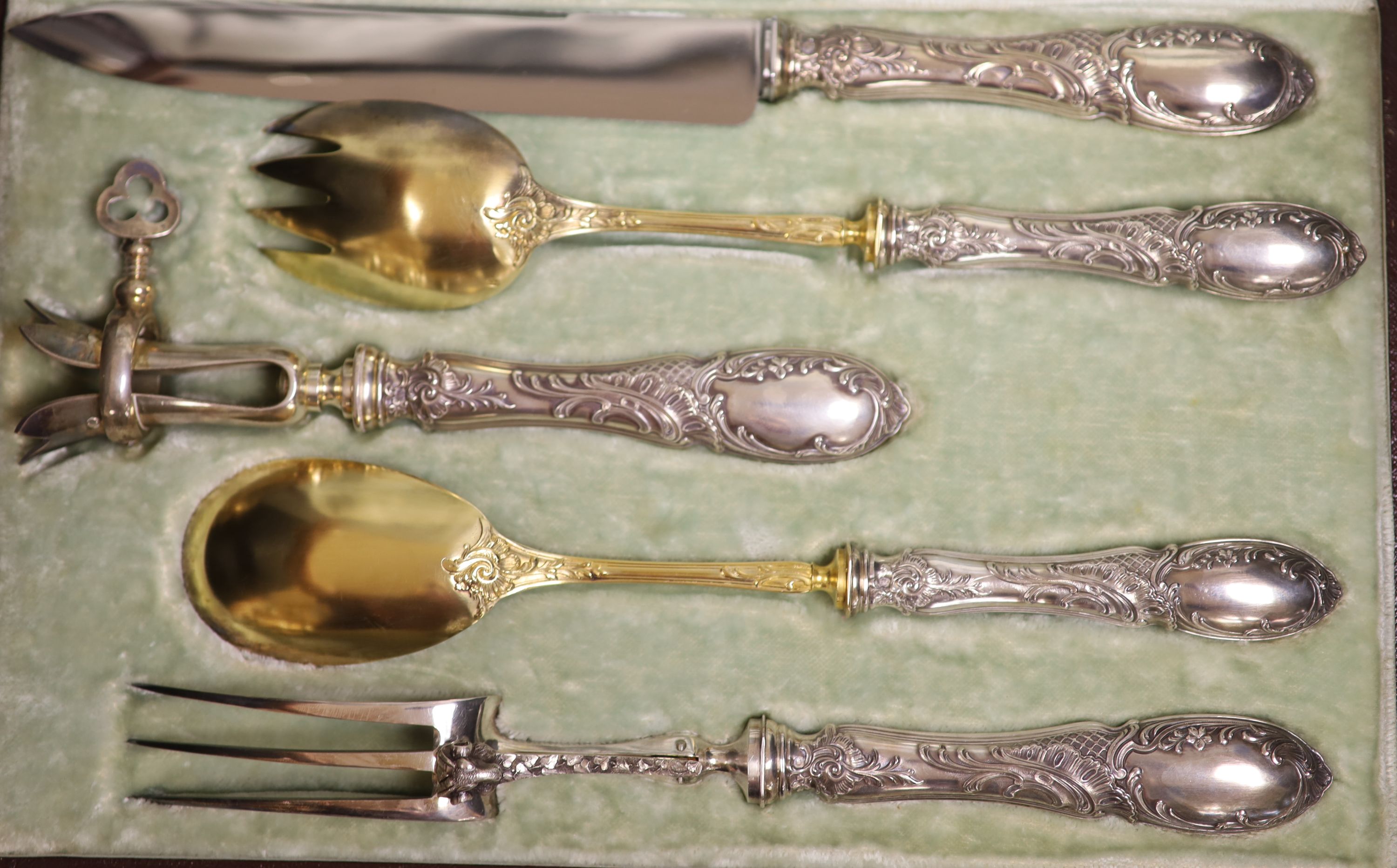 A cased early 20th century French five piece parcel gilt white metal and steel carving/serving set.